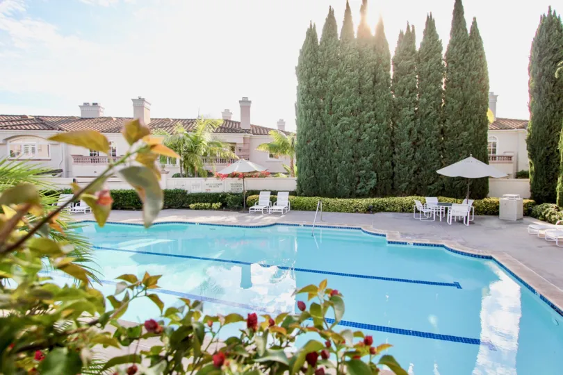 Large swimming pool with ample deck space and tall mature trees for privacy at Casabella in University City, CA