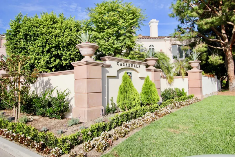 A SUNNY DAY IN THE CASABELLA HOUSE WITH LAWN, TREES, PLANTS.