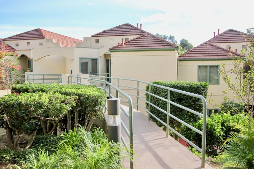 Raised walkway terrace overlooking housing units and professional landscaping at La Jolla City Club in University City, CA