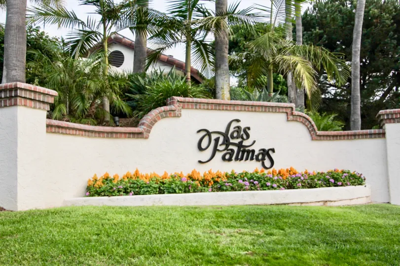 The entry sign with tropical landscaping, palm trees and flowers at Las Palmas in University City, California