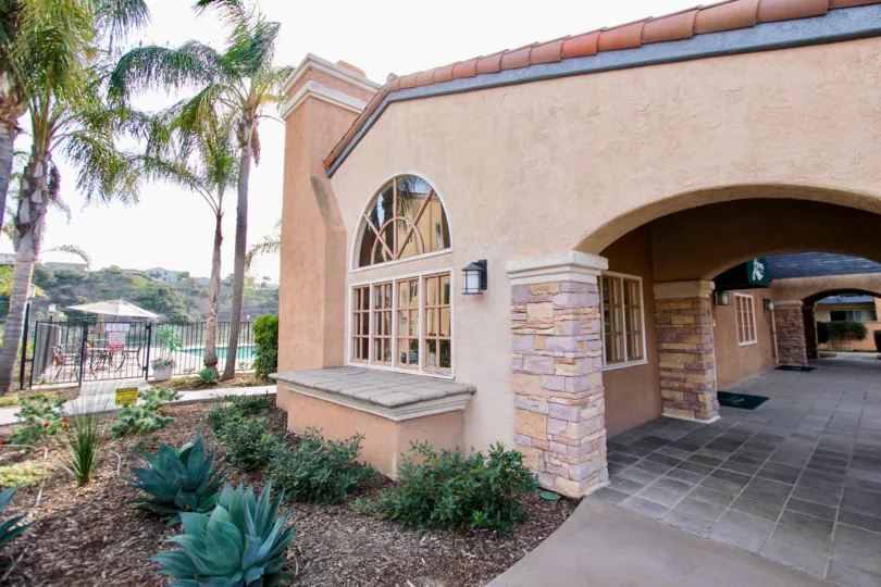 Single story pink home with arches & plants in University city CA at Lucera