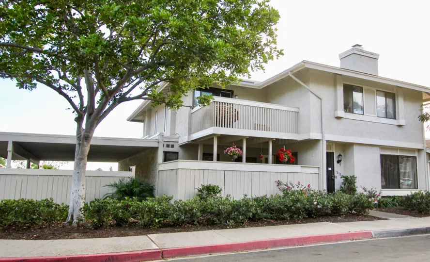 A white property with sidewalk and landscaping at Playmor Terrace West