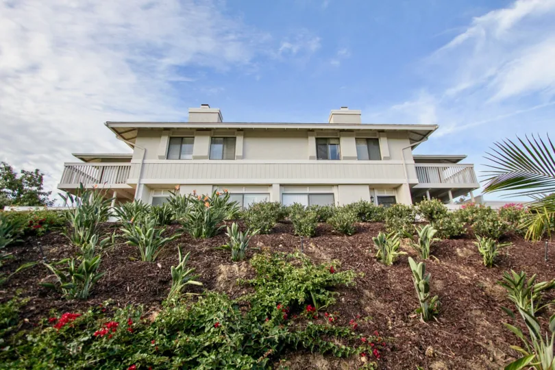 A side view of a house with blue sky and plants with a balcony on either sides at Playmor Terrace West