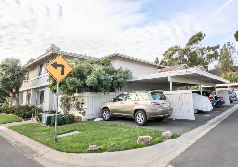 A yellow & black left turn sign at the corner of Playmor Terrace West in University City CA