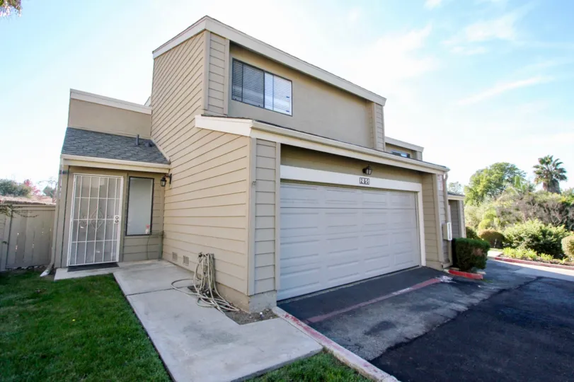 A modern looking house with a front lawn and a driveway and some trees on the side during a sunny day in Durian Place Townhomes, Vista, CA