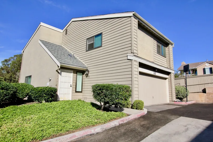 A two storey gray house with some bushes during a sunny day in Durian Place Townhomes, Vista, CA