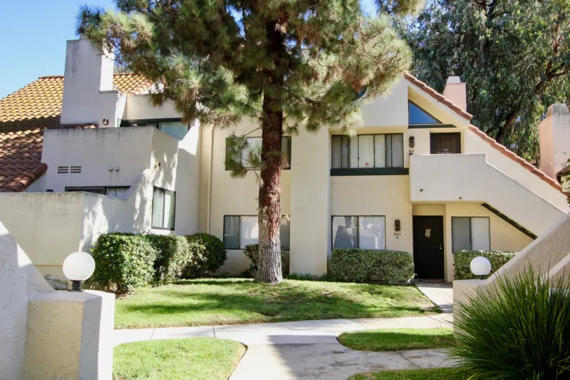 A tall tree is placed front of the Melrose Park community Villa in the meadow