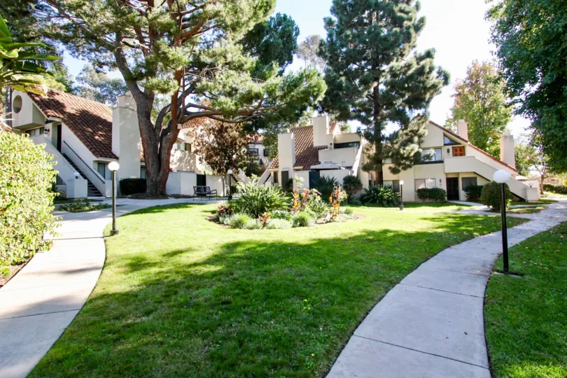 green lawn and flower bed between sidewalks lined with lamp posts in the Melrose Park neighborhood in Vista, California