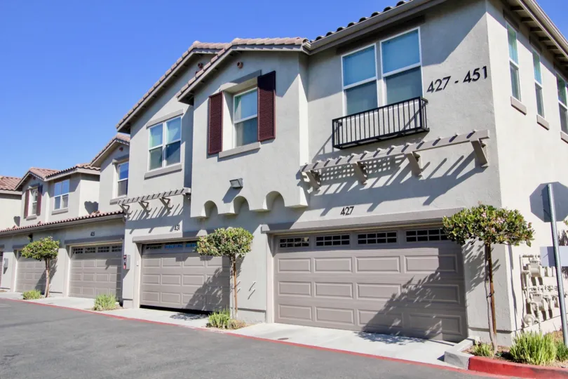 A series of gray townhouses with spanish tile roofs in the Santa Fe Walk community of Vista, CA