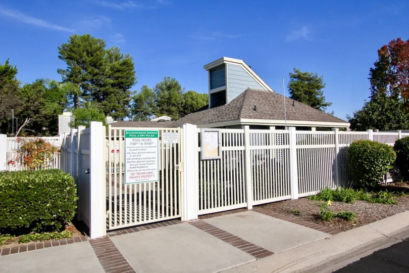 A sunny day in the area of Shadowridge Greens, fence, pool rules, trees