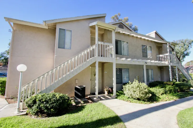 A two-story house with some bushes and lamp posts during a sunny day in The Park, Vista, CA