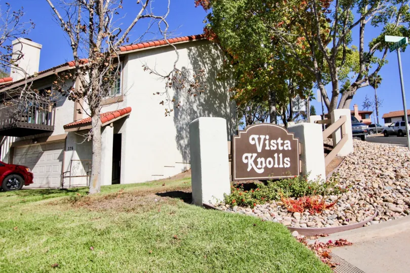 A sunny day in the area of Vista Knolls, car, welcome sign, tree, stairs