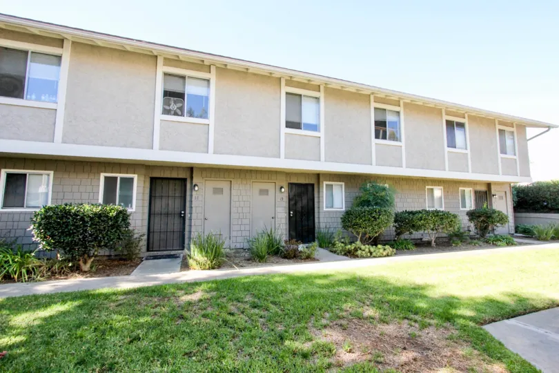 Hillside covered in grass with a gray residential building with many windows in Vista Ladera in Visa CA
