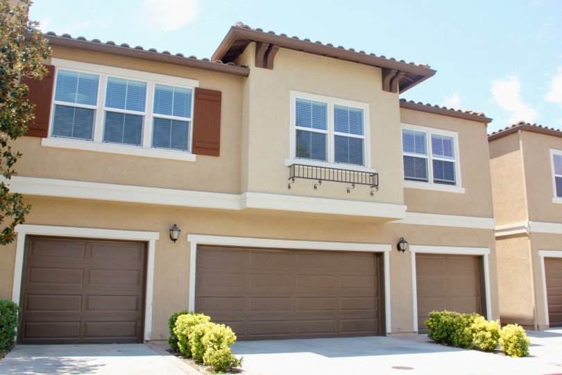 Condo garage with shrubs and large garage doors among trees and gardens