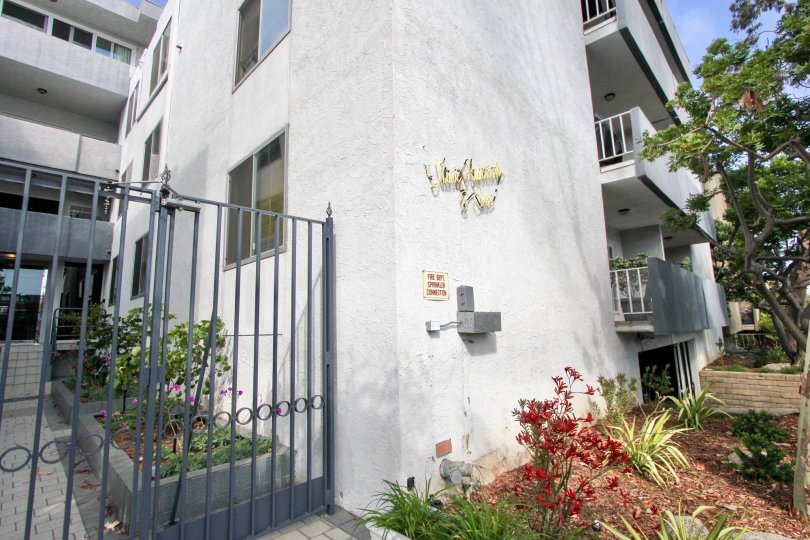 A white building in the 901 10th St community with a black fence and red flowers