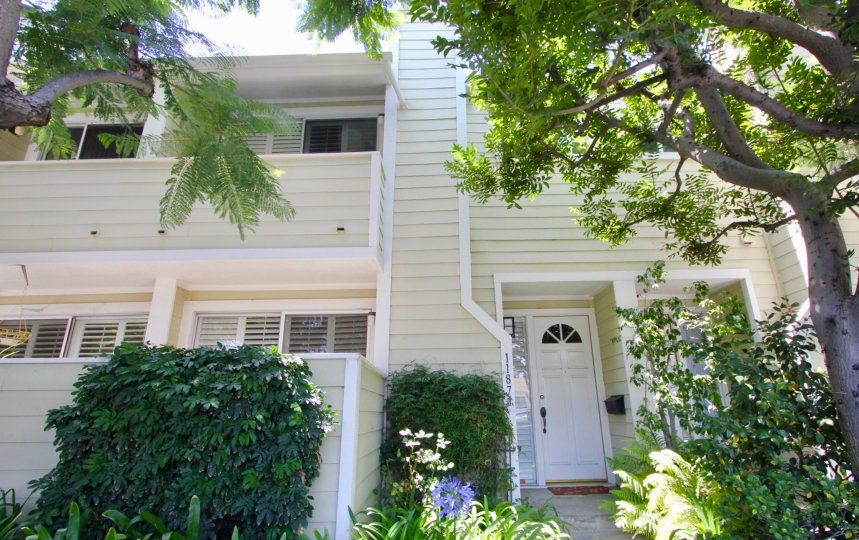 Entrance to Nebraska Manor Townhomes with white door, trees and bushes