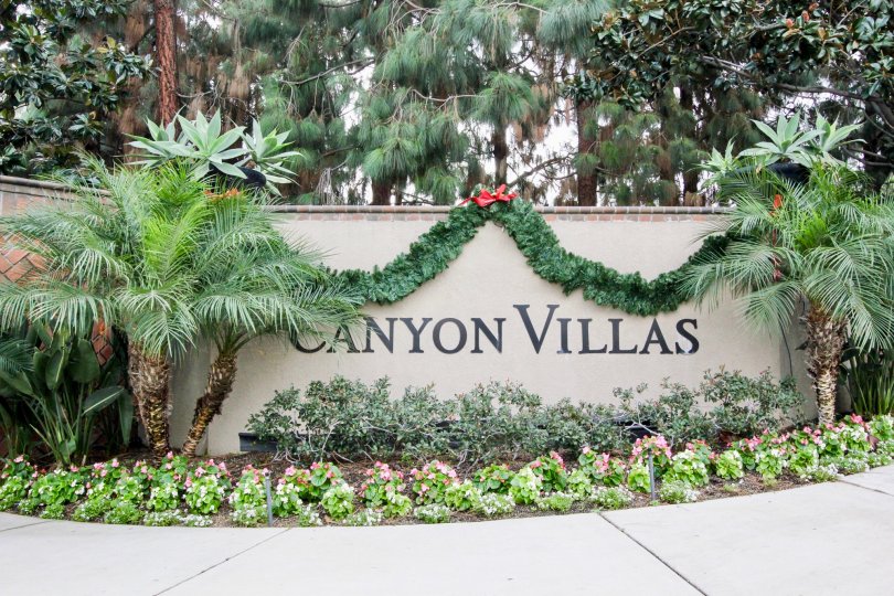 Plants and garland draped over entry sign at Canyon Villas in Aliso Viejo, California