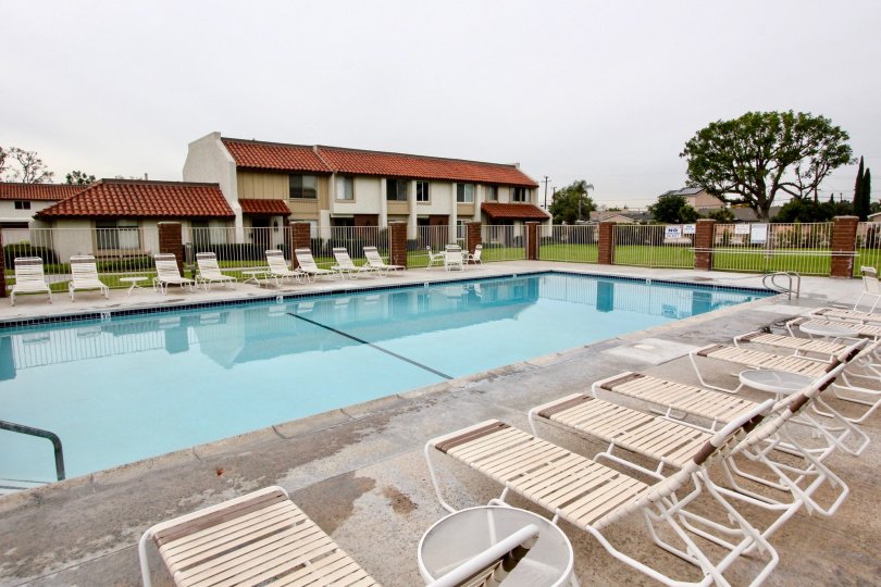 THE SWIMMING POOL IN CASITAS CALIFORNIA, THAT HAVE LOT OF CHAIRS SURROUNDED THE WALL BEHIND THE TREES