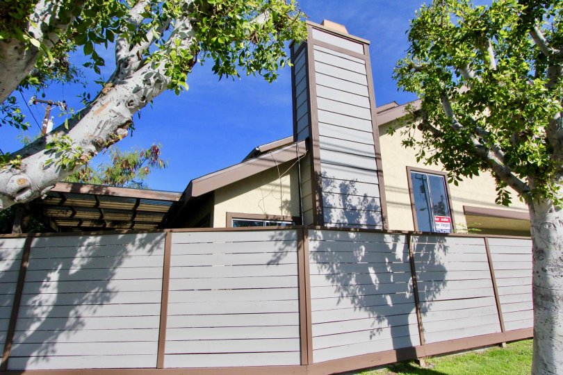 a sunny day in the stanford plaza with a building that has roofless in top and closed the gate