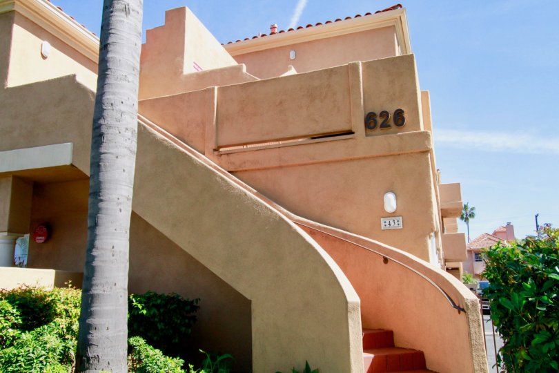 Villas Del Mar staircase with a palm trees and bushes on a sunny day.