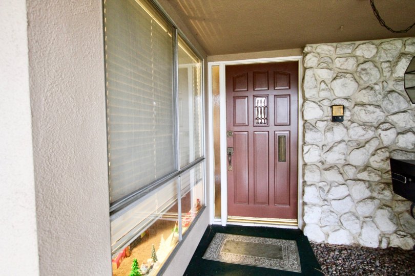 In front of a wooden door at Woodridge Townhouse with rock wall.