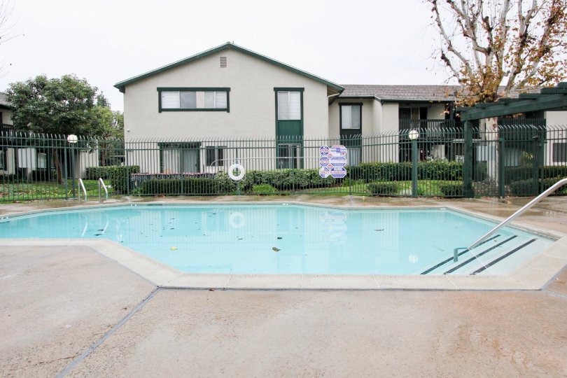 View of pool in Aliso Creek Villas in Lake Forest, California. Pool has handrail to assist with entry/exit of pool. Pool area is fenced.