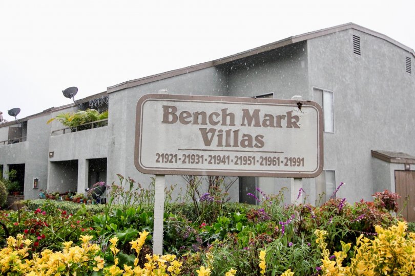 A gray building in the Bench Mark Villas community in Lake Forest, CA with yellow and purple flowers