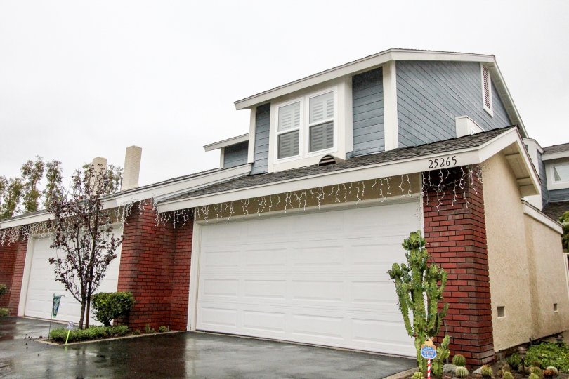 A black, shiny wet driveway sits in front of a garage in the San Remo Villas community