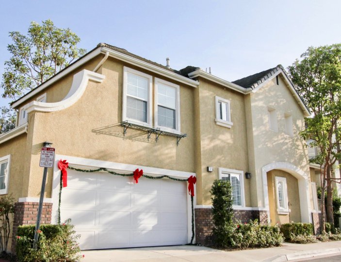 A sunny day at a house in the Magnolia area with Christmas decorations around the garage door as well as a couple trees and plants by different sides of the house
