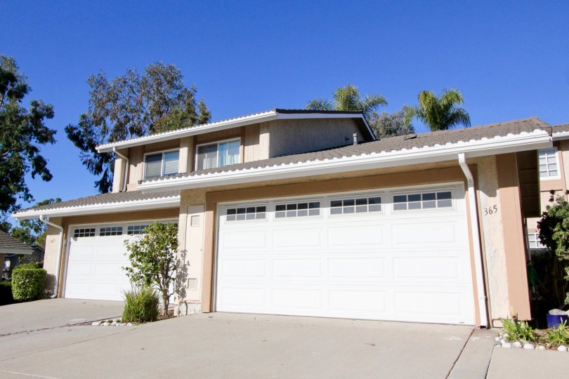 A small flower patch with bushes sits between two garage doors at Mira Costa Villas