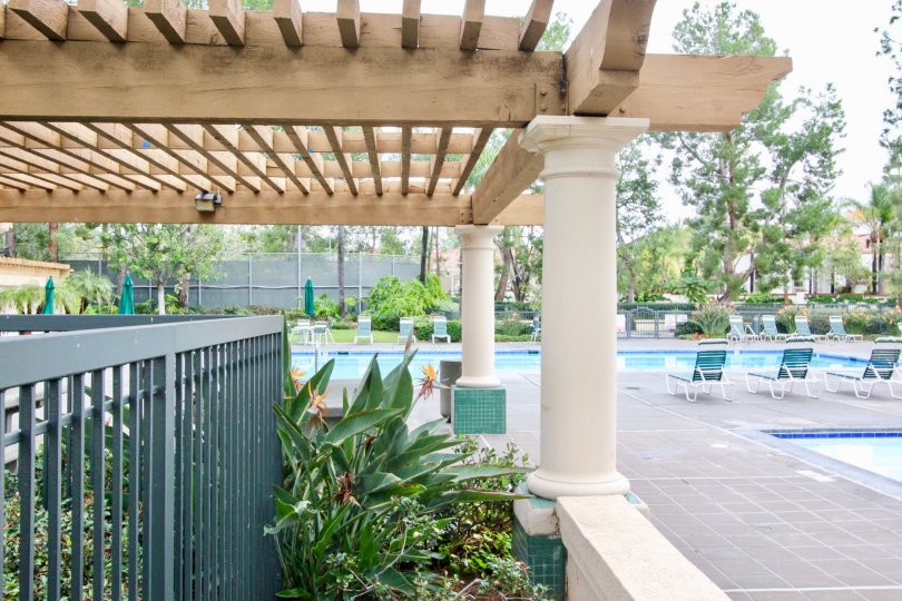 The swimming pool area, complete with chairs and a lovely pergola in the community of Corte Villa in Tustin, California