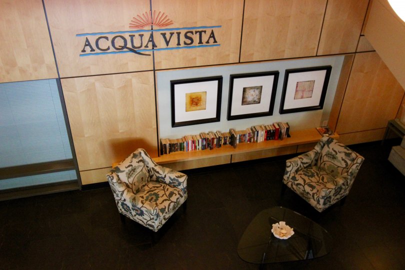 Two chairs and framed pictures under community sign at Acqua Vista in Downtown San Diego CA