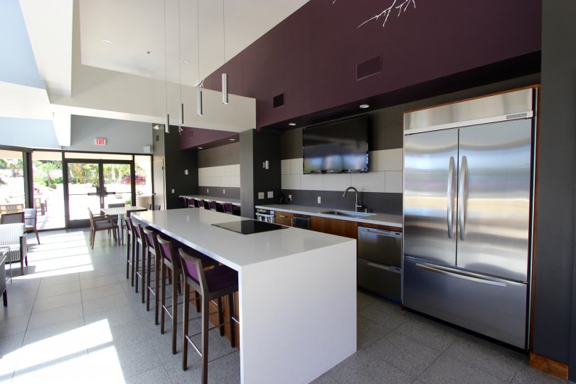 An interior view of the sleek and modern dining lounge at the Harbor Club with stainless steel appliances and plum colored accents.