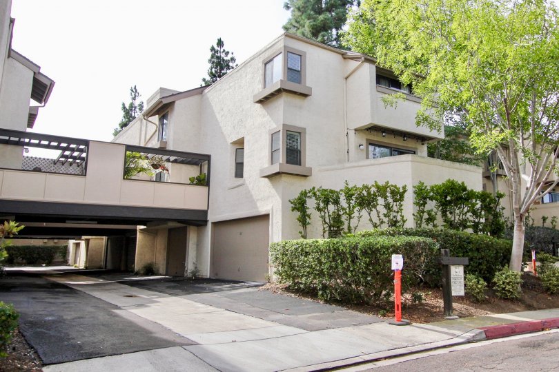 A gray house with some bushes and trees at the front and some garages at ground level in Woodlands West I, La Jolla, CA