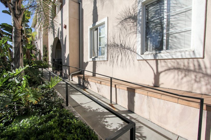 Gray paved sidewalk lined with plants at villa Portofino on Front in Mission HIlls CA