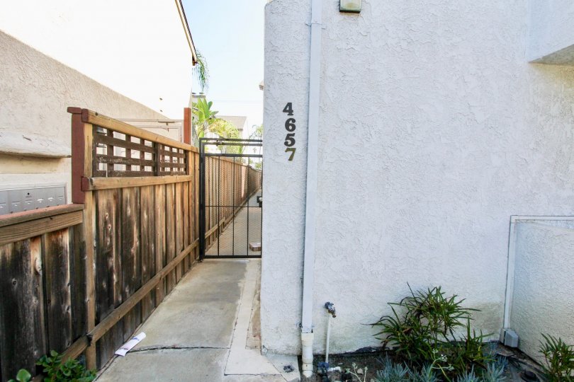 A closed black gate next to a wooden fence alongside the A2I Condominiums in Normal Heights, California.