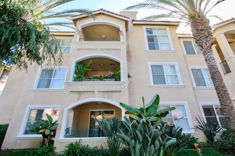 Three story building with tropical landscaping and porches at La Costa Villas in Oceanside, California