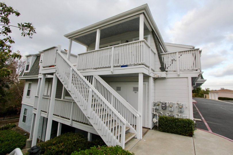White three story home with multiple balconies and stairs, located in Villa San Luis Rey, Oceanside, California.