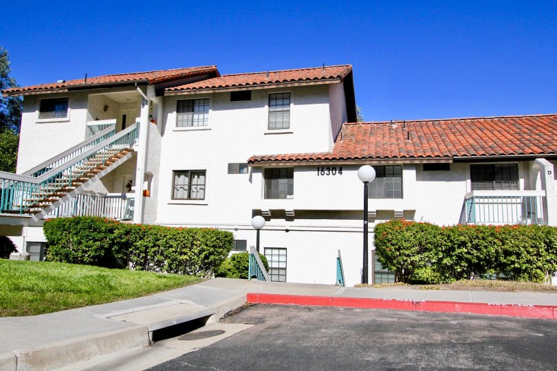 A white house with red roofing and some bushes in front at Mira La Paz, Rancho Bernardo, CA