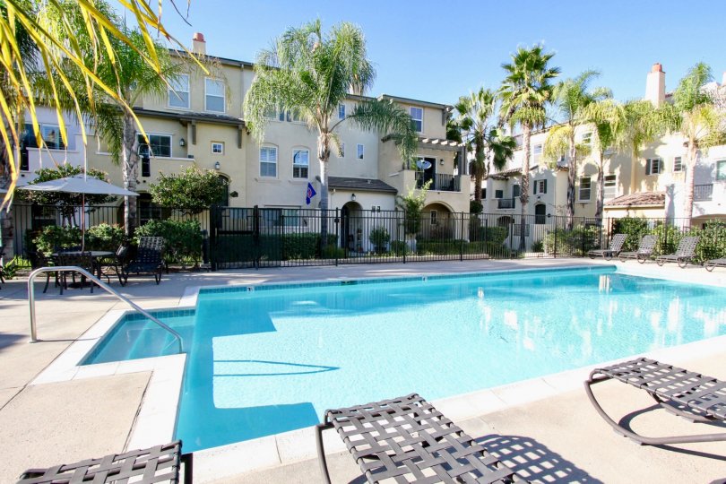 A sunny day in San Moritz has villa's with swimming pool, chairs and trees